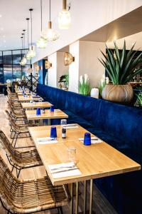 una fila de mesas en un restaurante con plantas en HOTEL RESTAURANT LA COTE REVEE, en Leucate