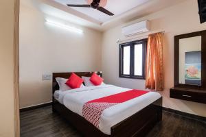 Un dormitorio con una cama con almohadas rojas y una ventana en OYO Seera Enclave en Rajahmundry