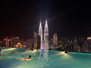 吉隆坡的住宿－Platinum Sky Park Kuala Lumpur，一座游泳池,晚上在水里的人在城市里