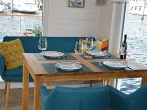 una mesa de madera con copas de vino y platos en ella en Houseboat Hecht in Egernsund at the Marina Minde en Egernsund