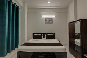 OYO Flagship Hotel Aanandwan Palace في فاراناسي: غرفة نوم بسرير كبير مع ستائر خضراء