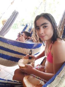 a woman sitting in a hammock holding a coconut at Chalet Villarrué, Izabalito in Izabal