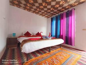 LukungにあるBlue Chill Cottage Pangongのベッドルーム1室(カラフルなカーテン付きのベッド1台付)