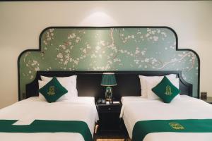 a bedroom with two beds with a large headboard at Goldient Boutique Hotel in Da Lat