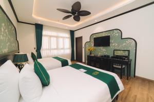 a bedroom with two beds and a desk and a ceiling fan at Goldient Boutique Hotel in Da Lat