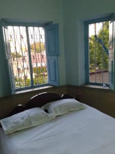 a bed with two pillows in a room with two windows at Shanthi House in Mysore