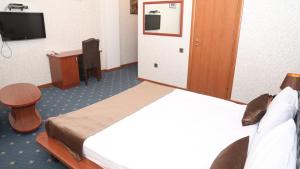 um quarto de hotel com uma cama, uma secretária e uma televisão em Hotel & Bistro em Baku