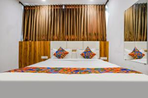 sypialnia z dużym białym łóżkiem z kolorowymi poduszkami w obiekcie FabHotel Prime Dumas w mieście Surat
