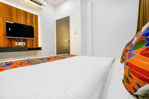 a bedroom with a white bed and a flat screen tv at FabHotel Prime Dumas in Surat