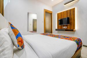 a bedroom with a bed and a tv on a wall at FabHotel Prime Dumas in Surat