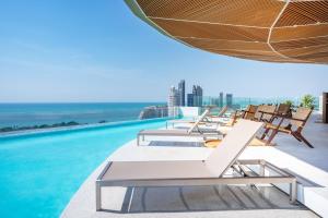 a row of lounge chairs on the edge of a swimming pool at Akara Hotel Pattaya in Pattaya North
