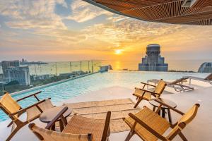 a pool on the roof of a building with chairs at Akara Hotel Pattaya in Pattaya North