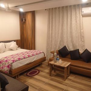 a hotel room with a bed and a couch at Hotel Shubh Ashish Near Bank More in Dhanbād