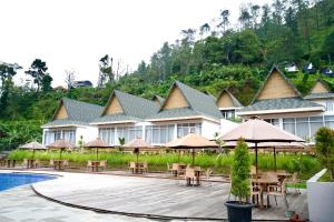 a resort with a pool and tables and umbrellas at Gulala Azana Hotel & Resort Guci Tegal in Tegal