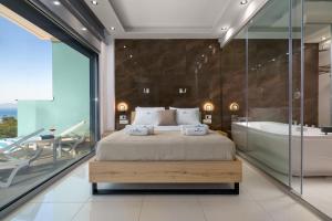 a bedroom with a large bed and a tub and a glass wall at RhodesRentalsgr presents Rhodes Skyline Suites in Ixia