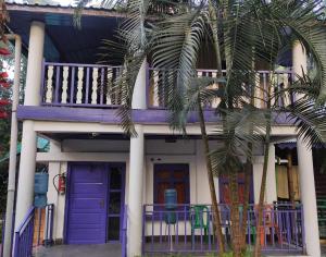 een huis met paarse deuren en een palmboom bij Sylvan Retreats in Lataguri