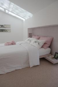 - une chambre avec un lit blanc et des oreillers roses dans l'établissement Villa Alma Vista, à Dobrovo