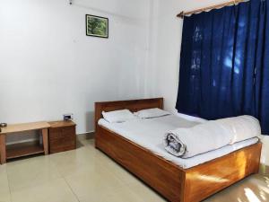 1 dormitorio con 1 cama con cortina azul en Sylvan Retreats, en Lataguri
