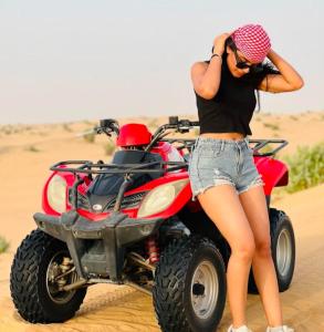 a woman talking on a cell phone next to a wheeler in the desert at Best Desert Camp In Jaisalmer Red Velvet in Jaisalmer