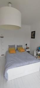 ein weißes Schlafzimmer mit einem großen Bett mit orangefarbenen Kissen in der Unterkunft Belle maison nantaise avec piscine in Nantes