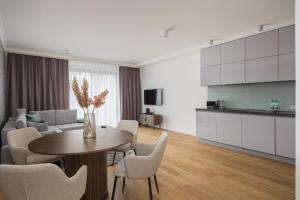 a kitchen and a living room with a table and chairs at Wilanów Branickiego Deluxe Apartment in Warsaw