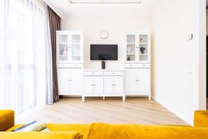 uma sala de estar com televisão e armários brancos em cohost I Sunny, Bright & New Apt w-Balcony @ Renesanso em Vilnius