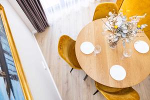 uma mesa de madeira com cadeiras e um vaso de flores em cohost I Sunny, Bright & New Apt w-Balcony @ Renesanso em Vilnius
