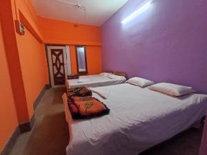 - 2 lits dans une chambre aux murs violet et orange dans l'établissement Nona Mati Lodge, à Gosāba