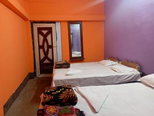 two beds in a room with purple and orange walls at Nona Mati Lodge in Gosāba