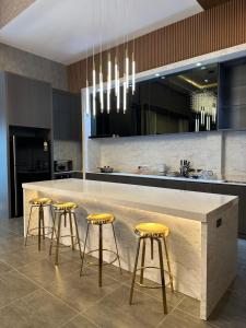a kitchen with a large counter with four bar stools at Chill Chill Pool Villa Pattaya in Nong Prue