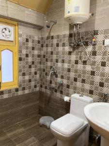La salle de bains est pourvue de toilettes, d'un lavabo et d'une douche. dans l'établissement Hotel Hill Valley, Ooty, à Ooty
