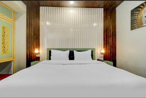 a bedroom with a large white bed with two lamps at Hi hotel By Madras in Rishīkesh