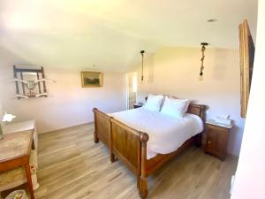 Cette chambre comprend un lit avec des draps blancs et du parquet. dans l'établissement Les Terrasses de Lô, à Bormes-les-Mimosas