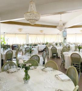 un comedor con mesas y sillas blancas y lámparas de araña en HOTEL IL SILLABARIO, en Iglesias