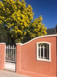 una valla naranja con dos ventanas y un árbol en Les Terrasses de Lô en Bormes-les-Mimosas