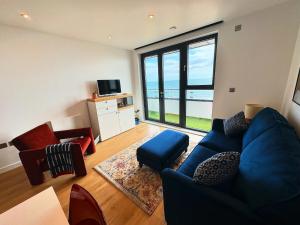 a living room with a blue couch and a large window at Stunning beach front apartment with sea views in Ramsgate