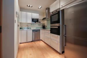 a kitchen with white cabinets and a stainless steel refrigerator at Ocean Village 2 bedroom apartment in Gibraltar