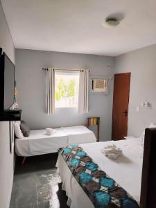 Habitación de hotel con 2 camas y ventana en Pousada Estalagem dos Corais da Prainha, en Arraial do Cabo