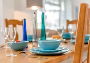 uma mesa de madeira com taças azuis e óculos em Seashells em Georgeham