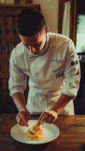 Un homme dans une cuisine préparant une assiette de nourriture dans l'établissement Le Charaban, à Aoste