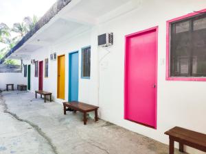 a row of brightly colored doors on a building with benches at Garpeza Backpackers in Port Barton