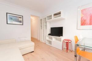 a white living room with a television and a table at 4 Rooms Playa Surf Cine- Parking y Terraza in Donostia-San Sebastián