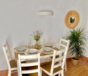 a dining room table with white plates and chairs at Beachfront Apartment in Cala Morell in Cala Morell