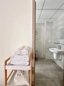 een witte badkamer met een wastafel en handdoeken op een plank bij Salt&Light Inn in Magong