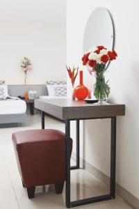 uma mesa com um vaso de flores e um espelho em Lee Nova Hotel em Bangna