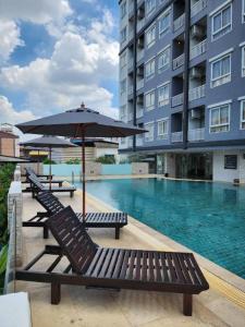 Duas espreguiçadeiras e um guarda-sol junto a uma piscina em Lee Nova Hotel em Bangna