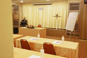 une salle de conférence avec deux tables et des chaises ainsi qu'un podium dans l'établissement Lee Nova Hotel, à Bangna