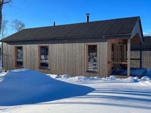 a house with a black roof in the snow at Naali in Kilpisjärvi