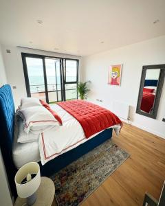 a bedroom with a bed with a red blanket at Stunning Beach Front Apartment with Sea views, FREE Parking & Balcony in Ramsgate