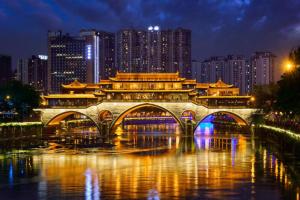 a bridge over a river in a city at night at Magnotel Hotel Chengdu Taikoo Li Dongfeng Bridge A in Chengdu